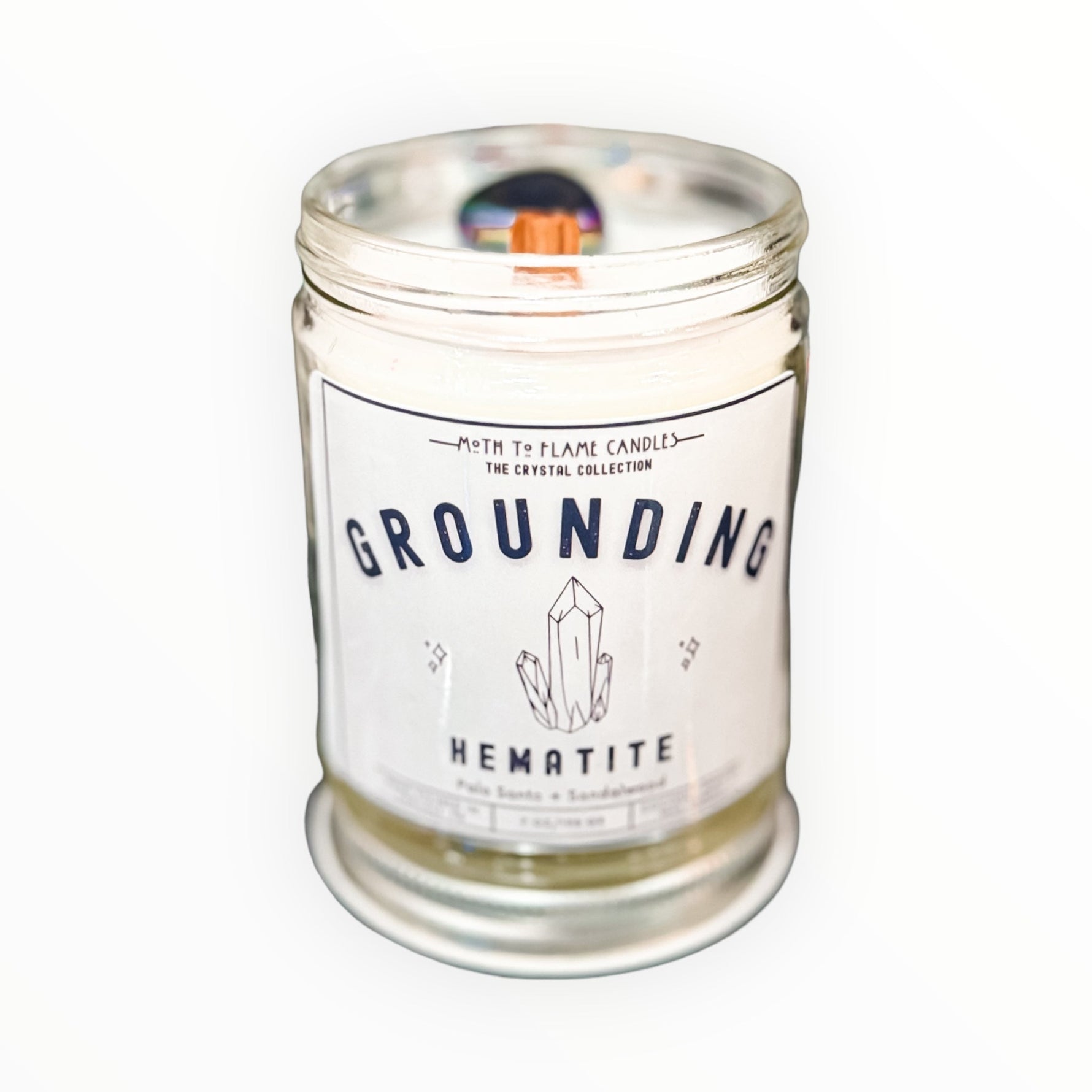 Candle in a glass jar labeled 'Grounding Hematite' on a white background